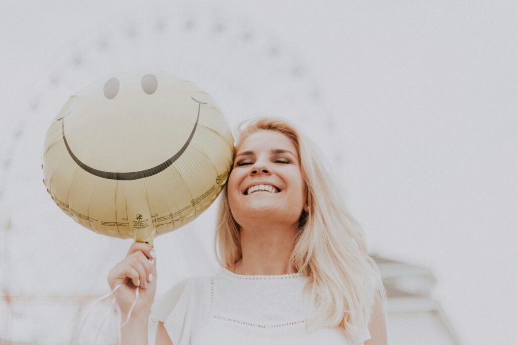 pexels photo 1236678 1236678 Cheerful woman holding a smiley balloon outdoors on a sunny day, exuding happiness and positivity.