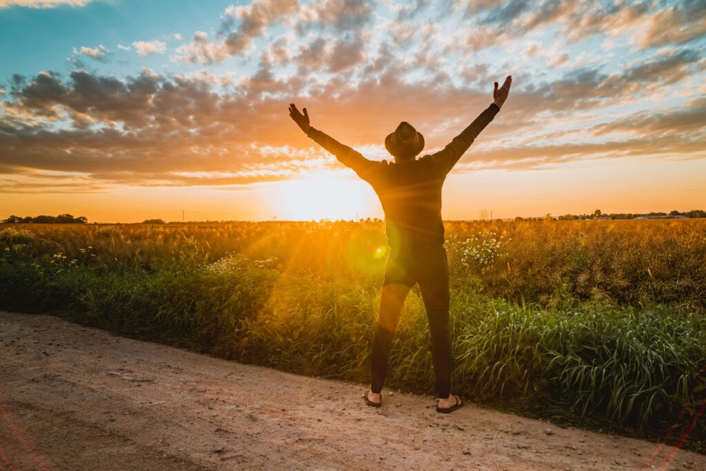 pexels photo 3827679 3827679 A man raises arms in freedom at sunrise in a rural field, expressing joy and connection with nature.